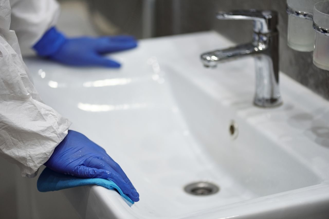 Home Close-up of a gloved professional cleaning a sink for sanitation.
